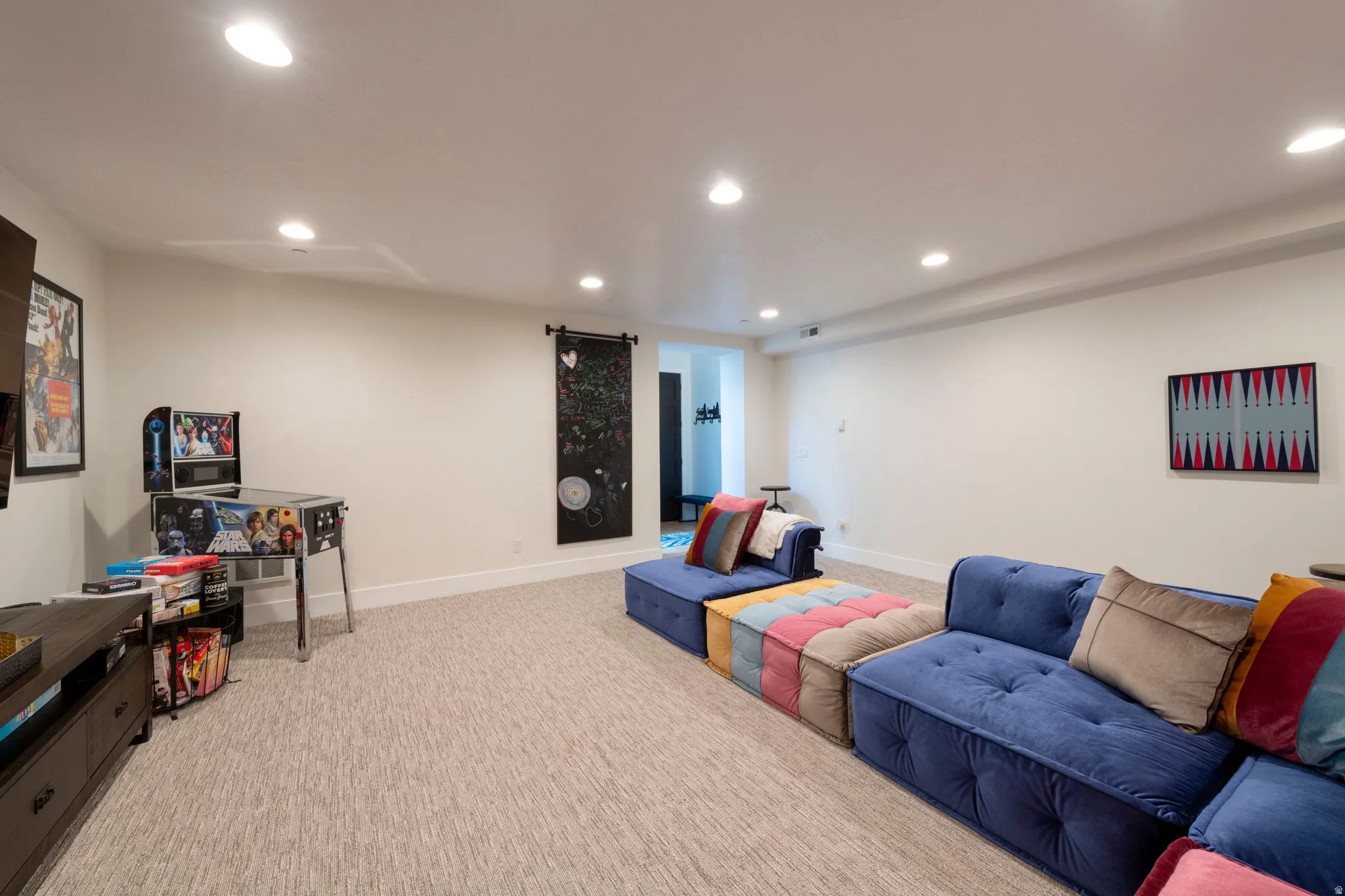 Recessed lighting, light-colored walls, and neutral carpet flooring