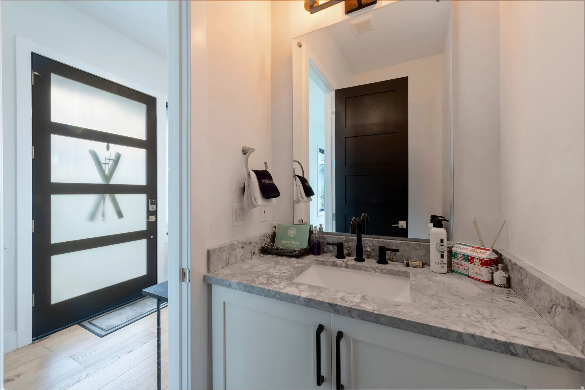 White vanity with black hardware, integrated sink, and stone countertop