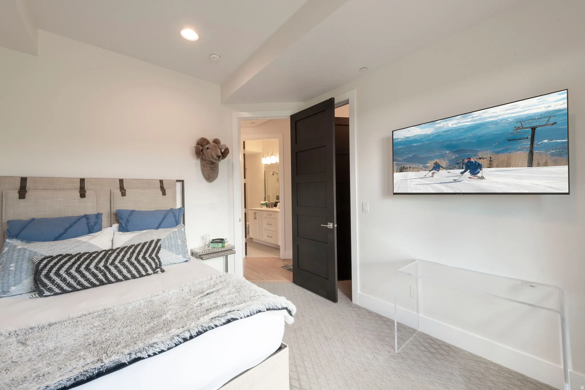 Recessed ceiling lighting, white walls, dark paneled door, light-toned carpet flooring, white bathroom vanity