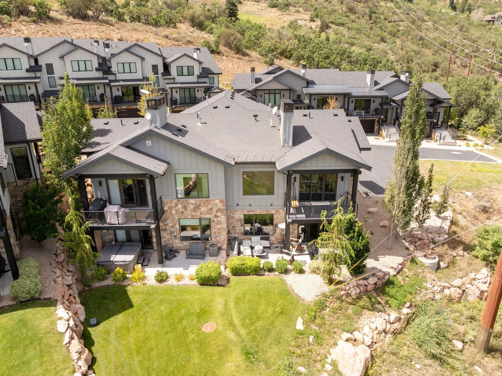 Contemporary residence featuring multiple balconies, stone detailing, and a manicured lawn