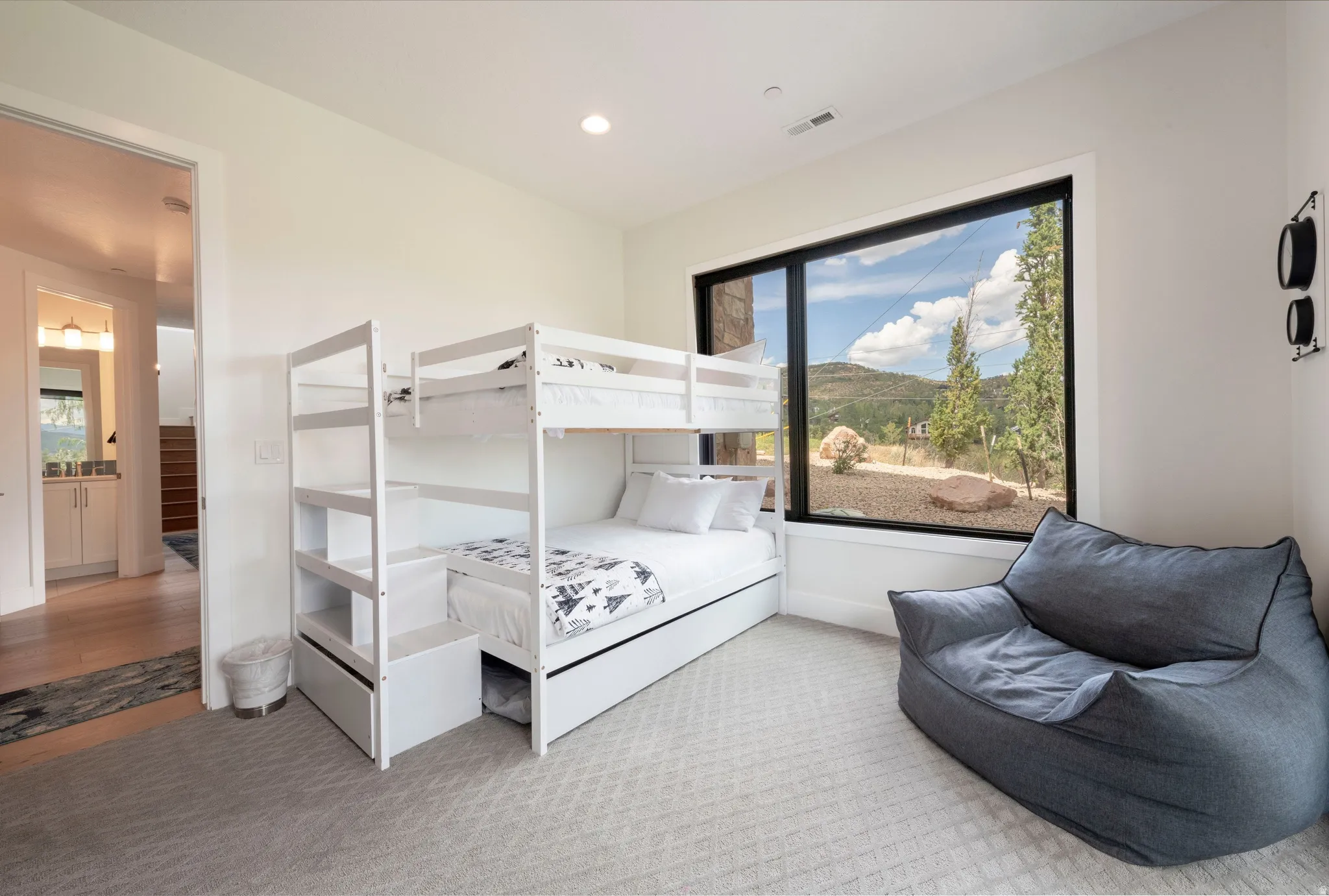 Full-light window with black trim, recessed lighting, wall-to-wall carpeting, and a built-in bunk bed structure with storage