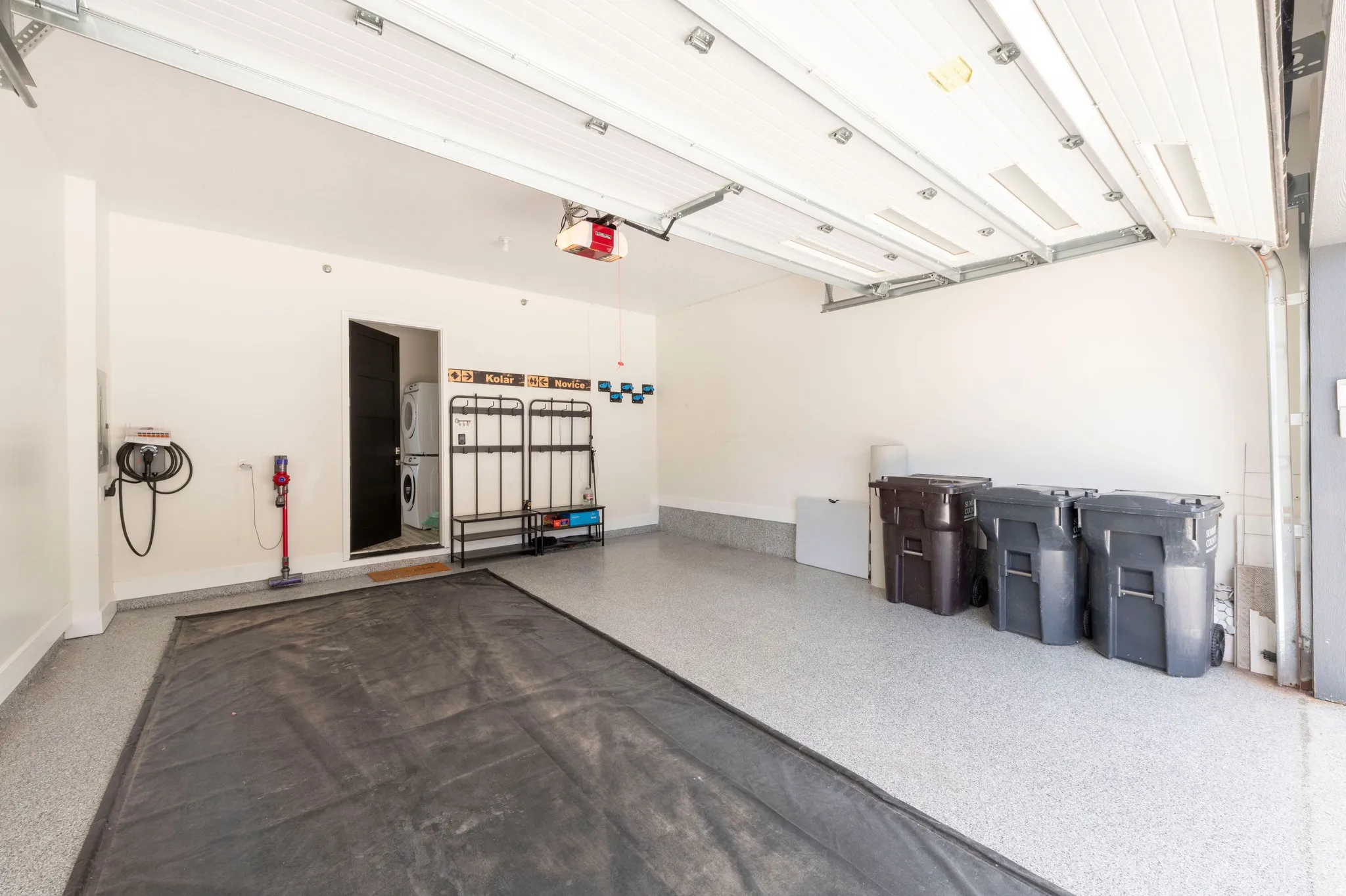 Garage with epoxy flooring, white walls, overhead lighting, and an internal access door