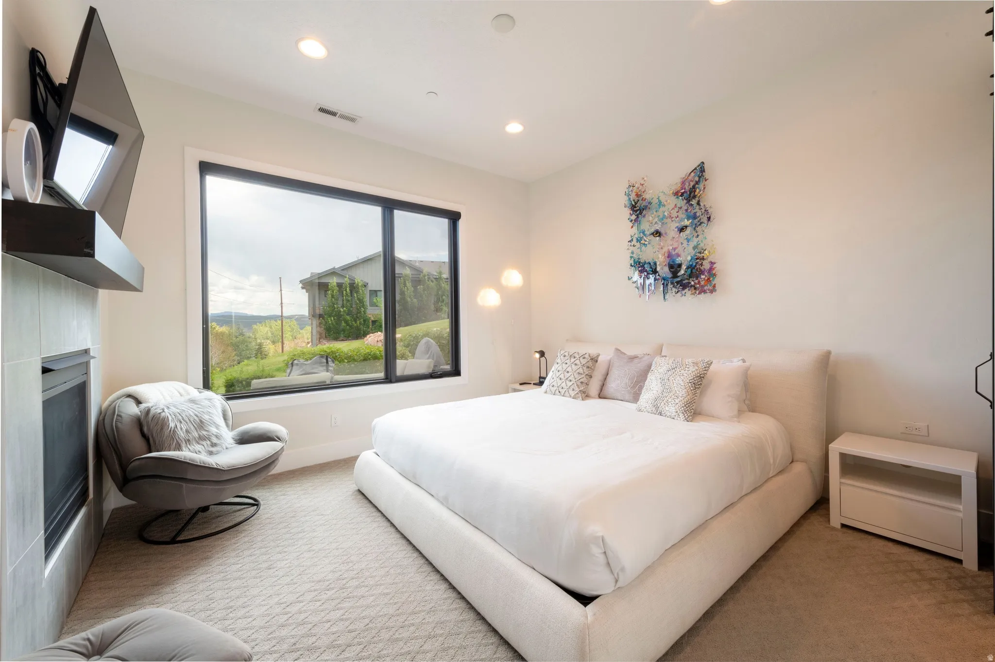 Recessed ceiling lighting, large window with black trim, built-in fireplace with tiled surround, and carpeted flooring