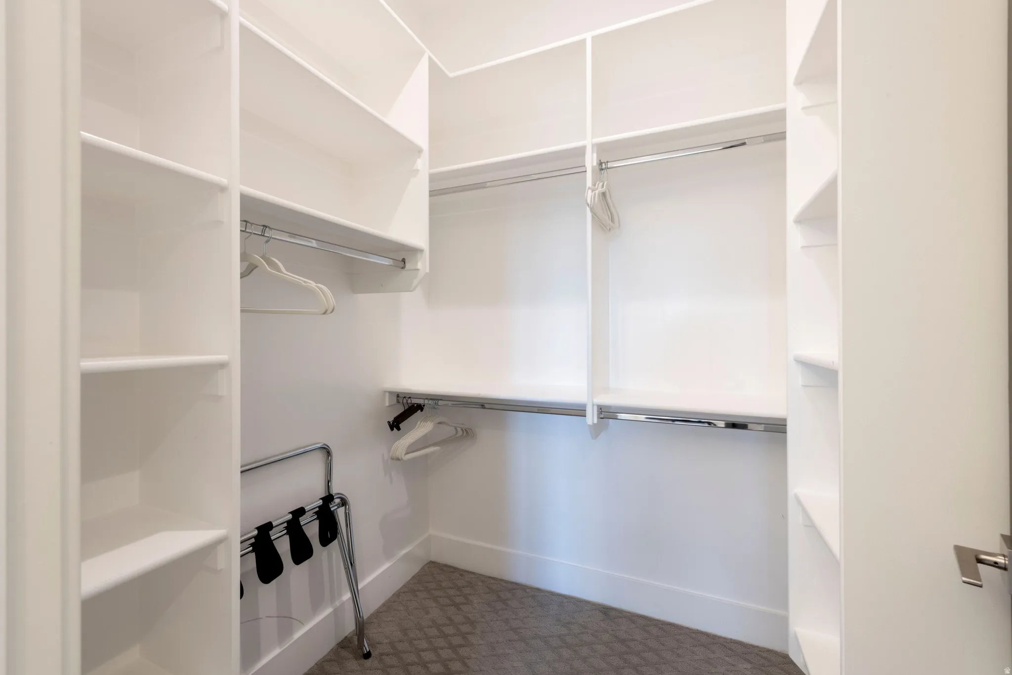 Custom closet system featuring multiple shelving units and chrome hanging rods