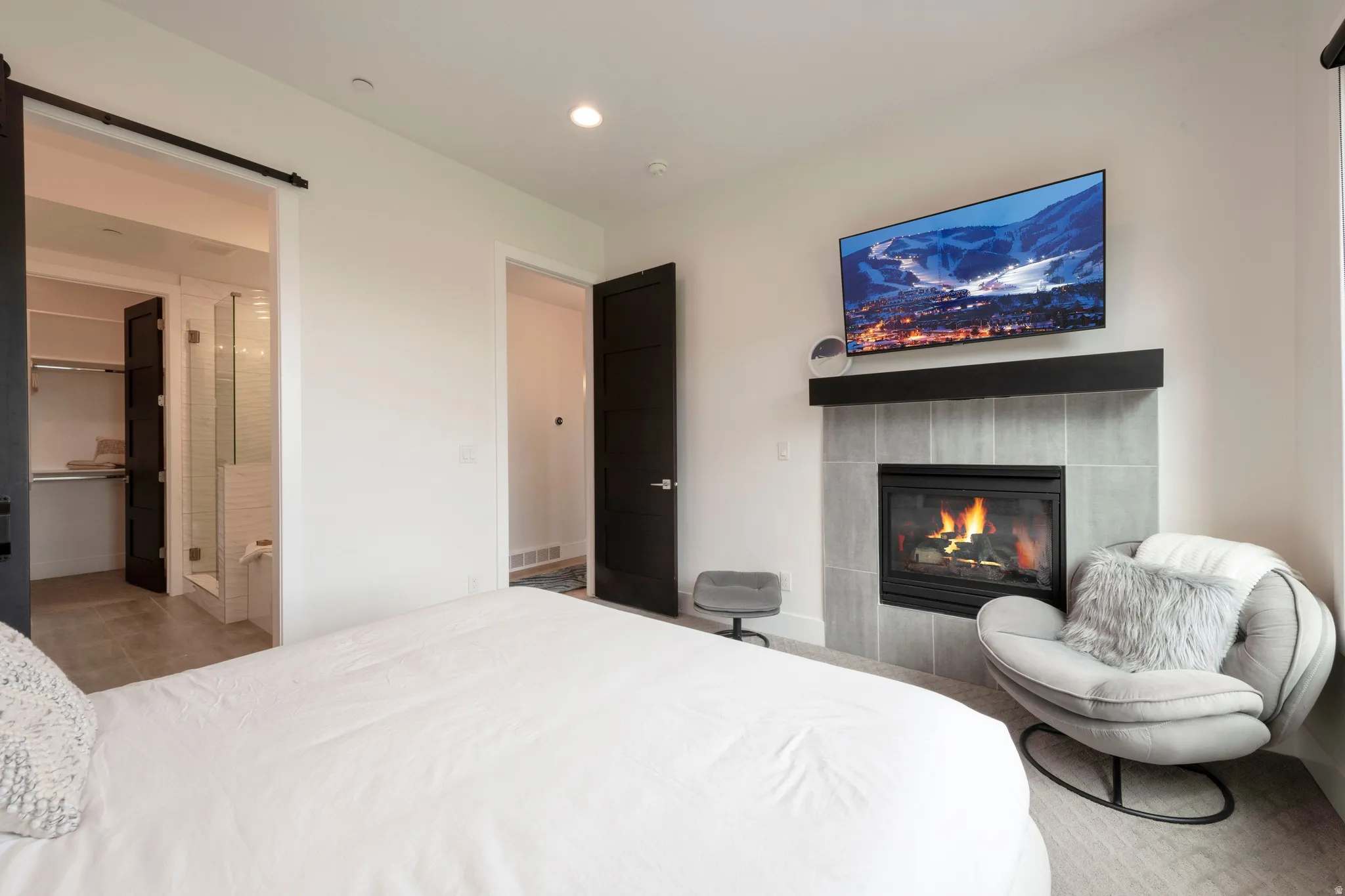 Tiled fireplace with a black mantel, recessed lighting, and barn door entry to an additional space