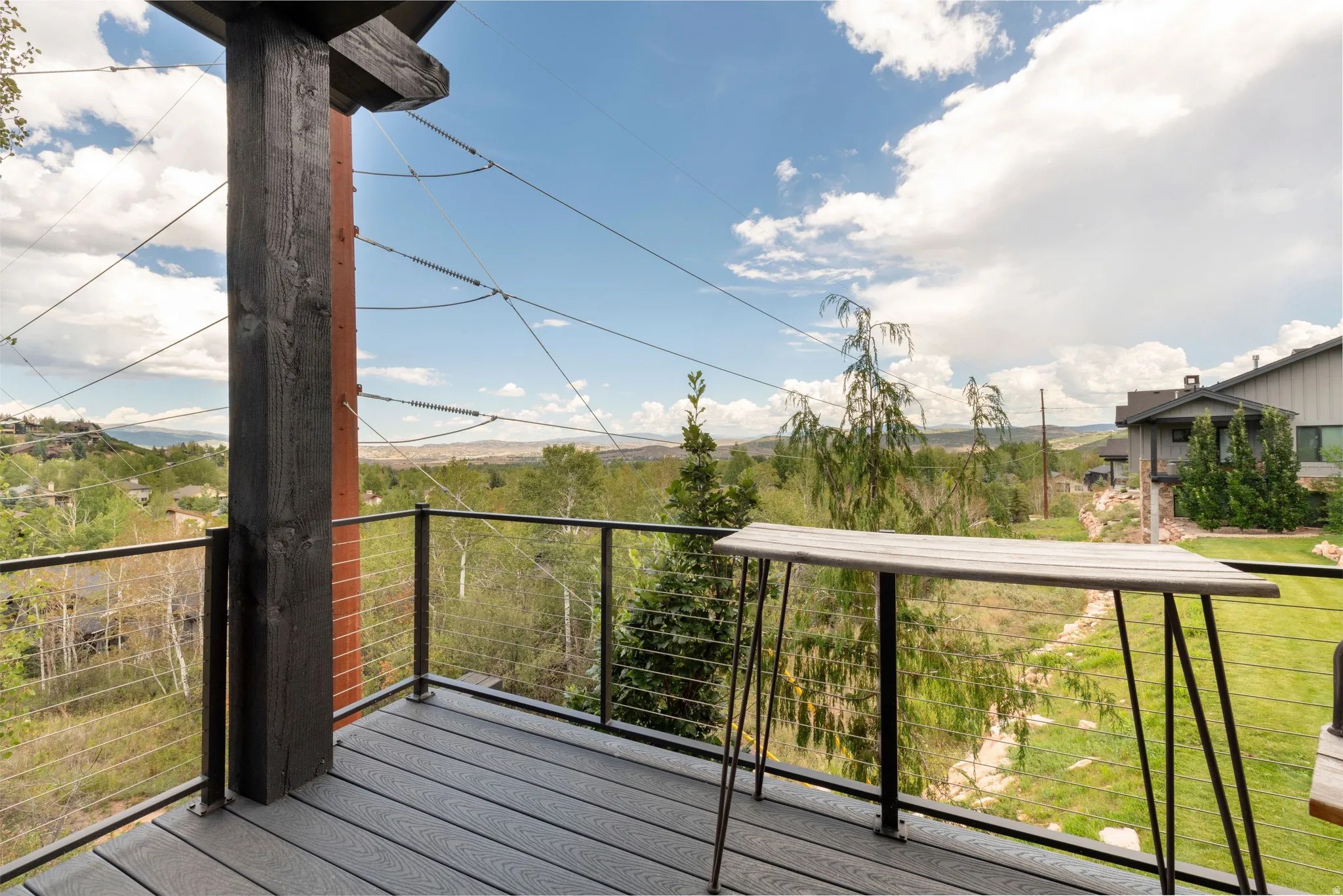 Exterior deck featuring composite decking, cable railing, and a prominent wood structural beam