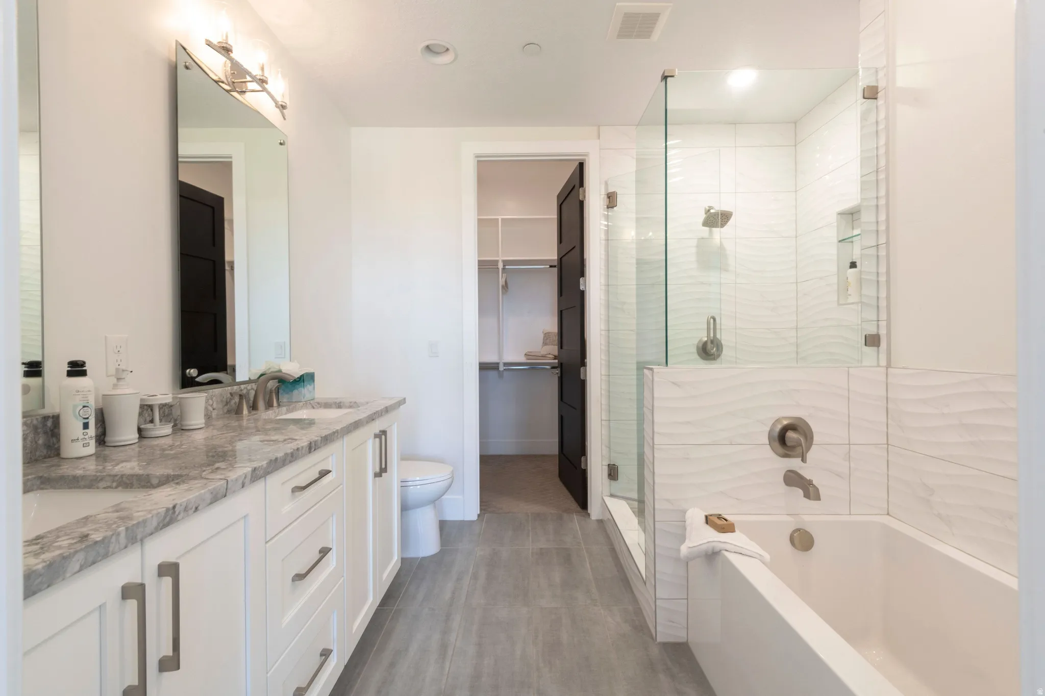Dual vanity with a stone countertop, individual mirrors, and modern light fixtures