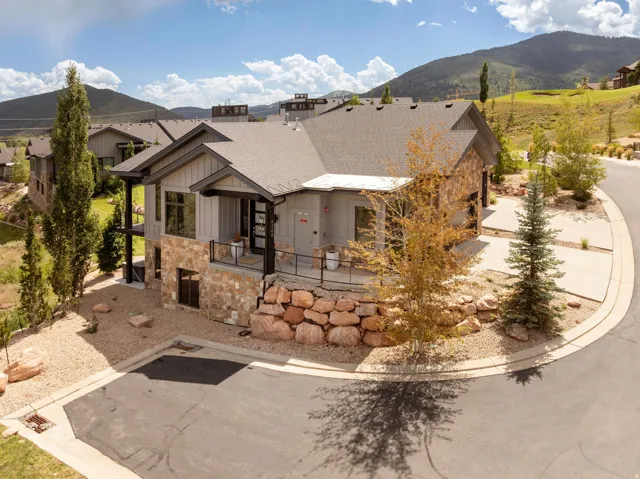 Modern exterior architecture featuring stone and vertical siding, a covered entry, an attached garage, and a paved driveway