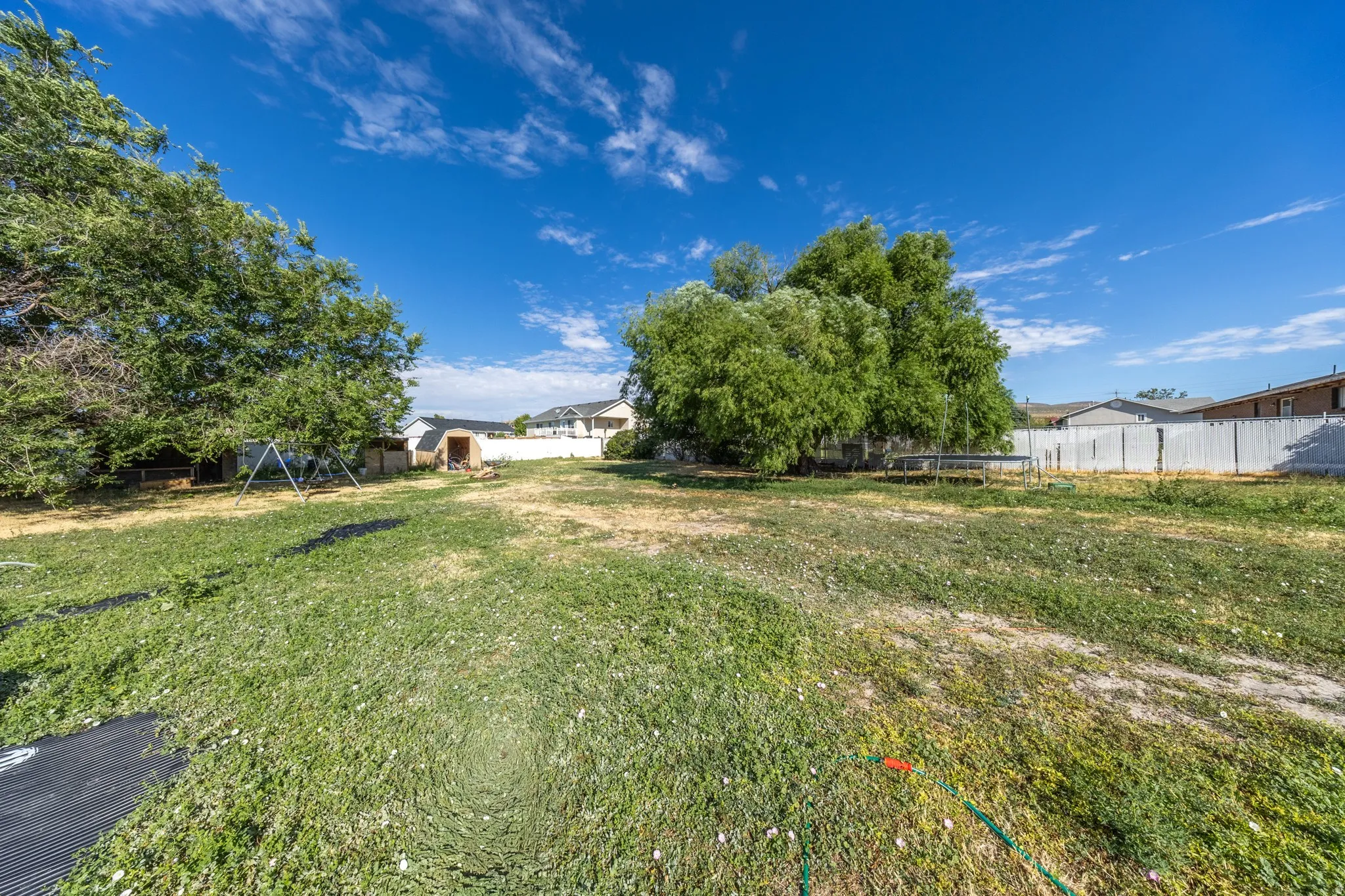 Expansive property featuring mature trees and a white privacy fence