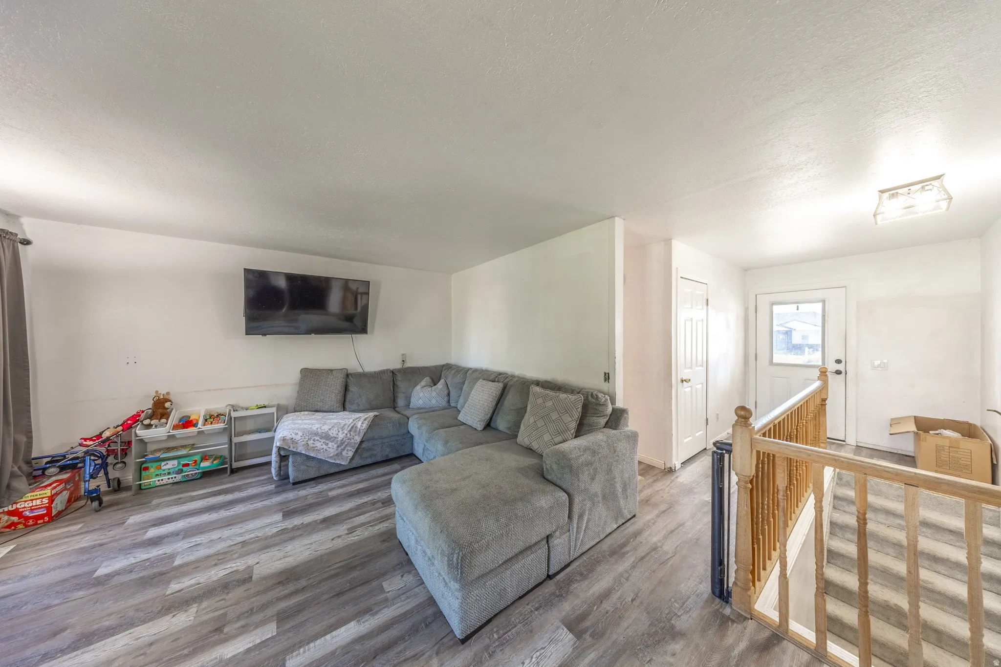 Wood-finish flooring, white walls, and a front entry door with a privacy window