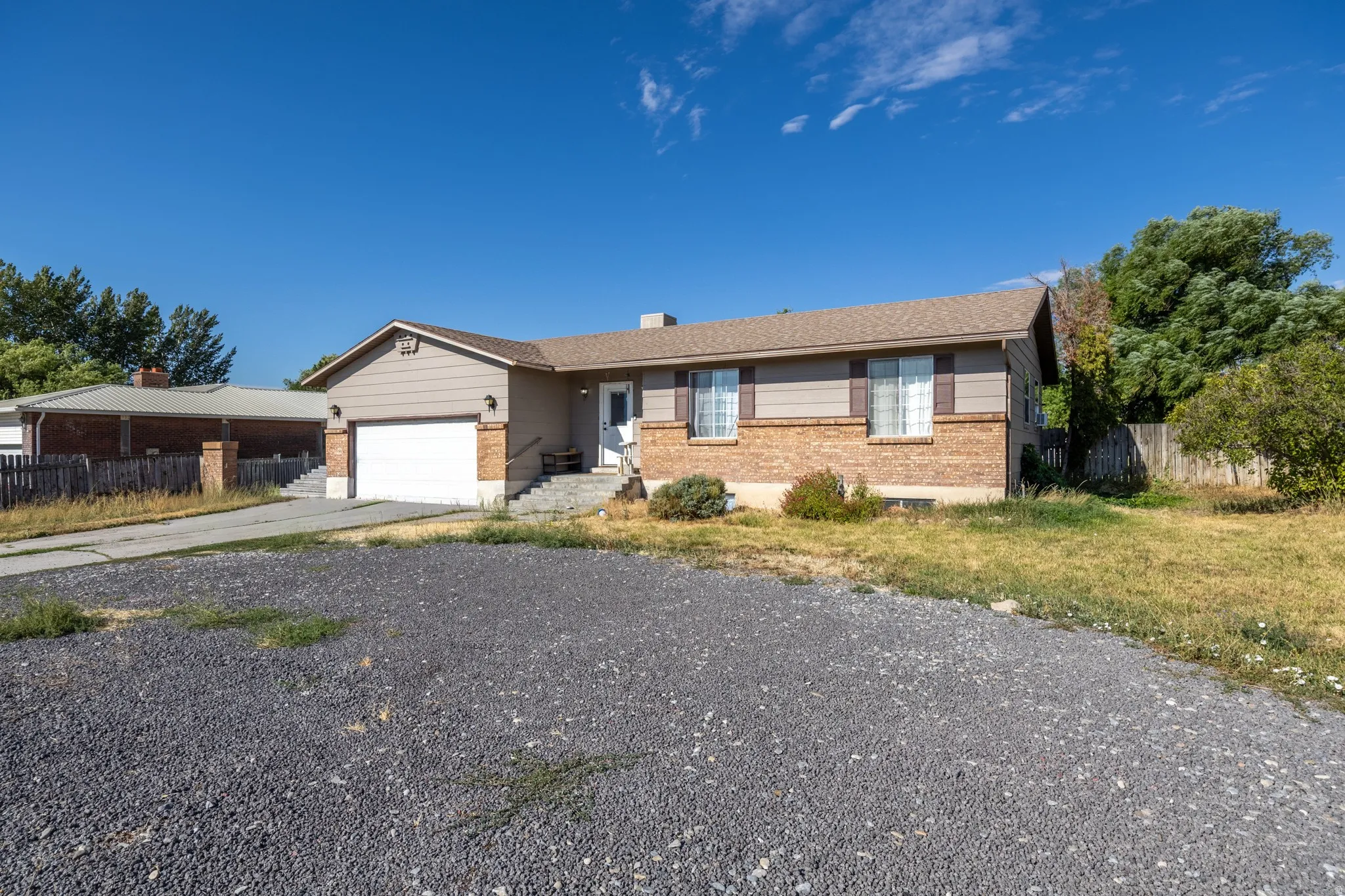 Ranch-style residence featuring a brick and siding exterior, attached garage, and a gravel driveway