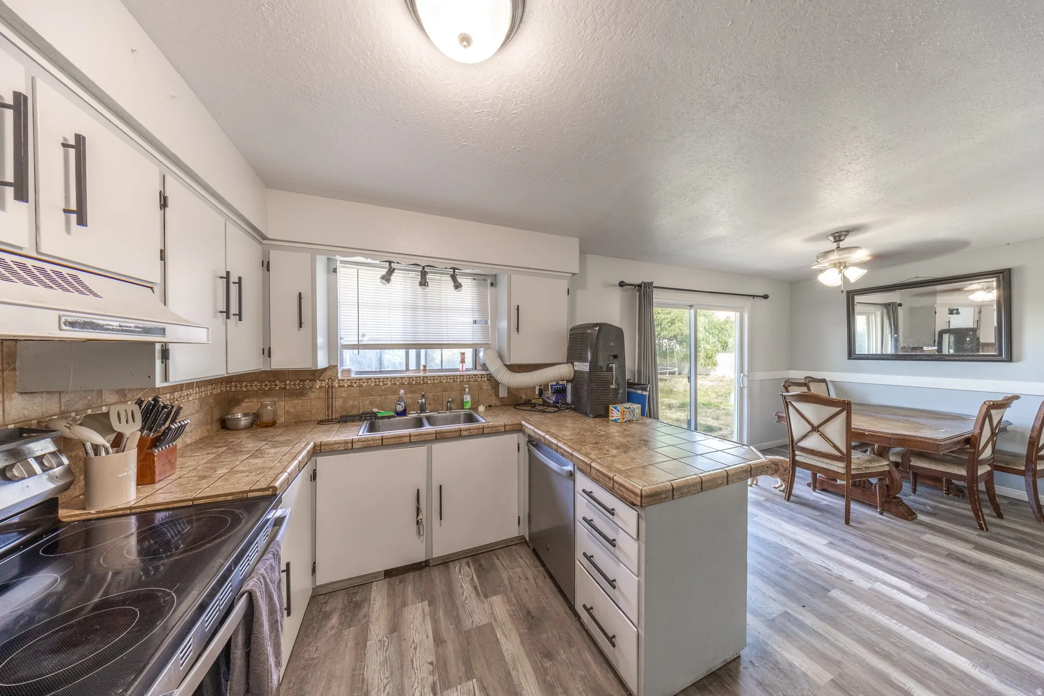 Kitchen with white cabinetry, tile countertops, and a stainless steel dishwasher
