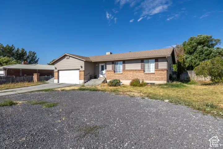 Ranch-style residence featuring a brick and siding exterior, attached garage, and a gravel driveway