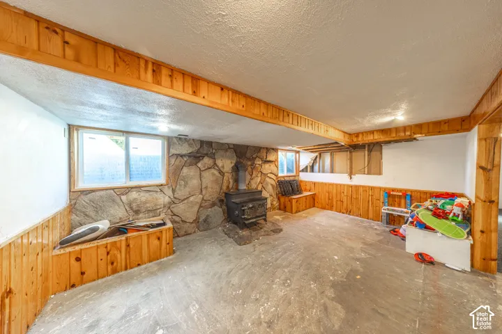 Stone-clad fireplace with a wood-burning stove, wood paneling, and built-in wood seating
