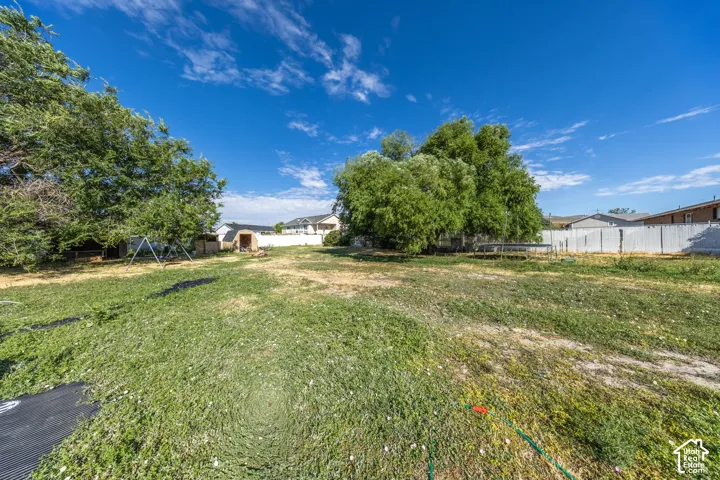 Expansive property featuring mature trees and a white privacy fence