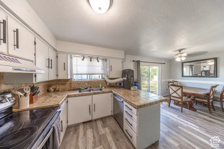 Kitchen with white cabinetry, tile countertops, and a stainless steel dishwasher
