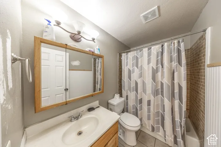 Bathroom featuring a single vanity with an integrated sink, a medicine cabinet with a wood-finish frame, a toilet, a full-size bathtub, and a tiled shower surround