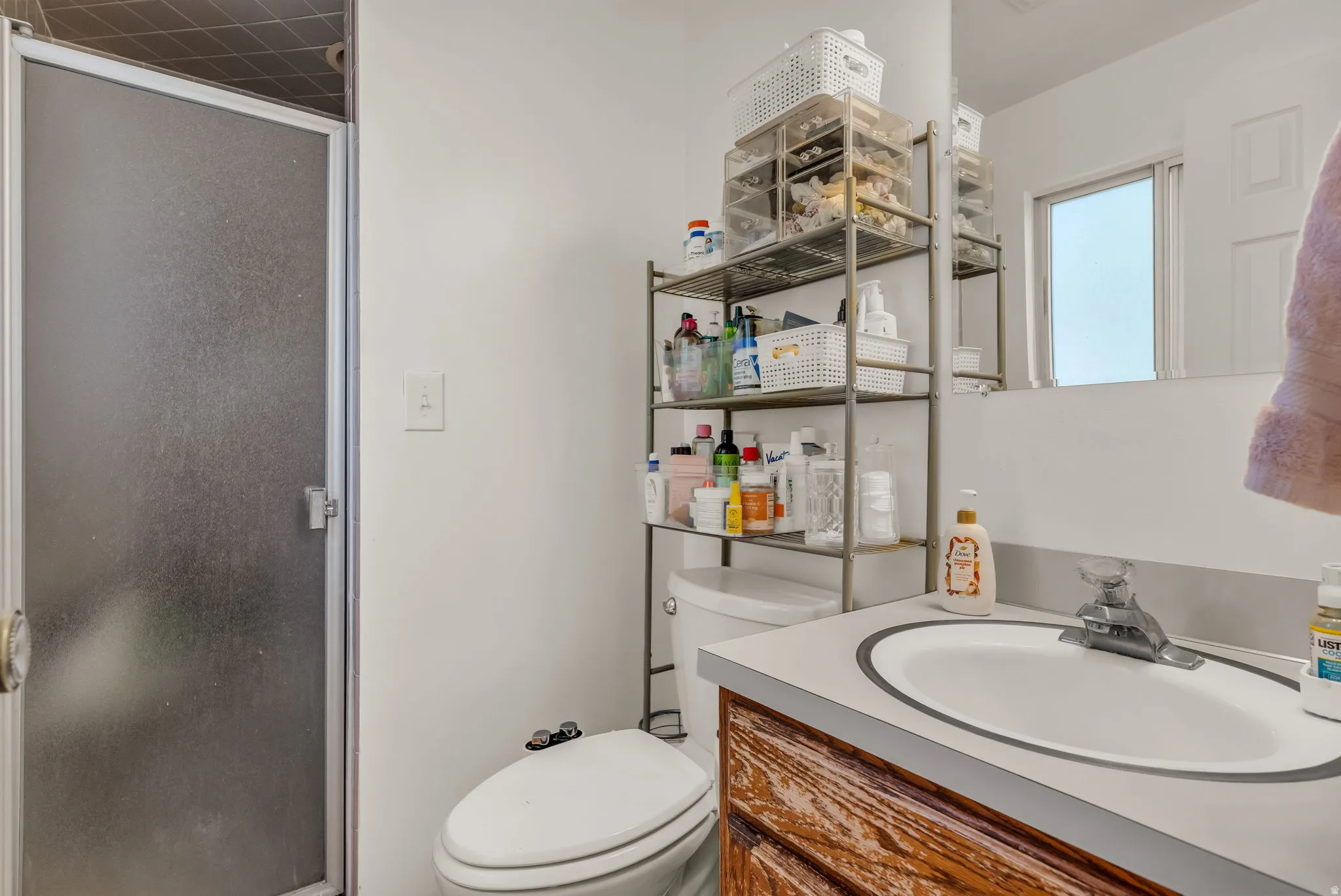 Functional bathroom featuring a round sink with wood-finish vanity cabinetry, chrome faucet, and white ceramic toilet