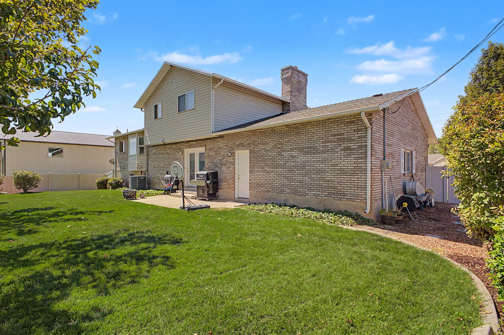 Expansive rear yard featuring a brick facade, siding upper level, and a concrete patio