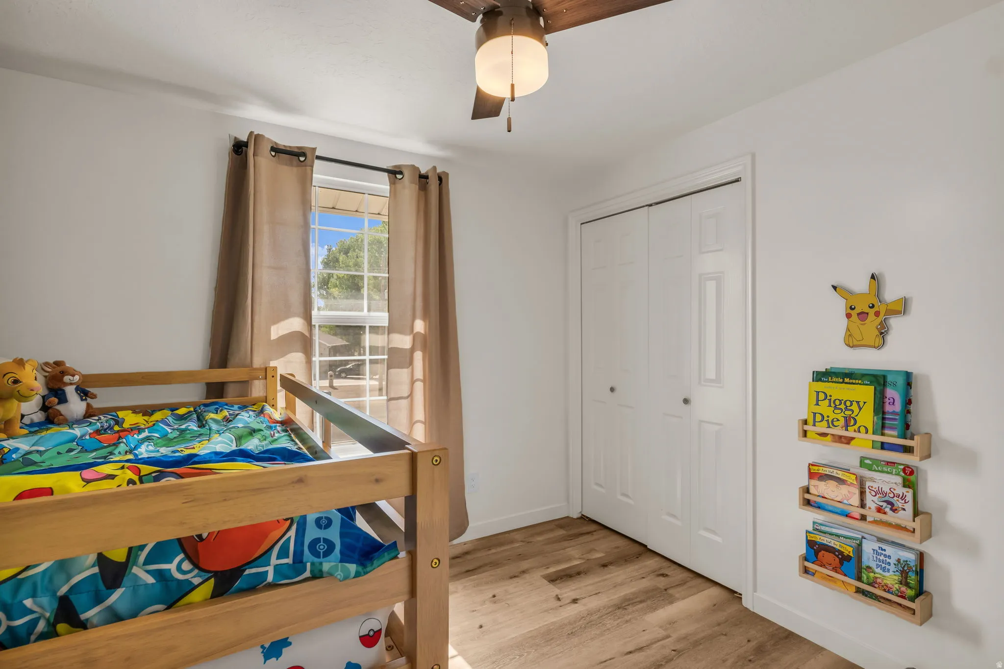 Wood-finish flooring, white walls, ceiling fan with integrated lighting, and bi-fold closet doors