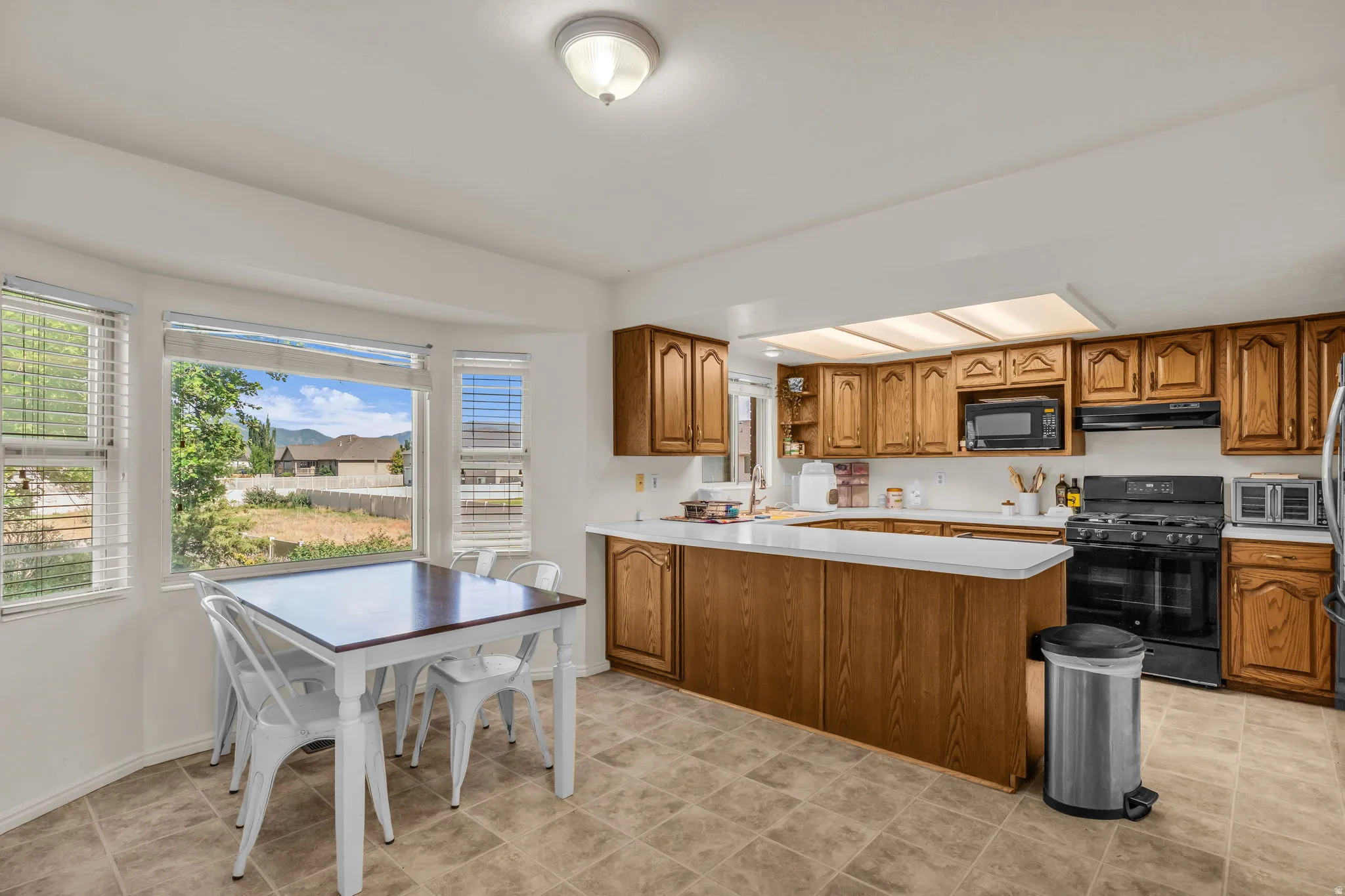 Kitchen featuring wood-finish cabinetry, white countertops, a black gas range, and a built-in microwave