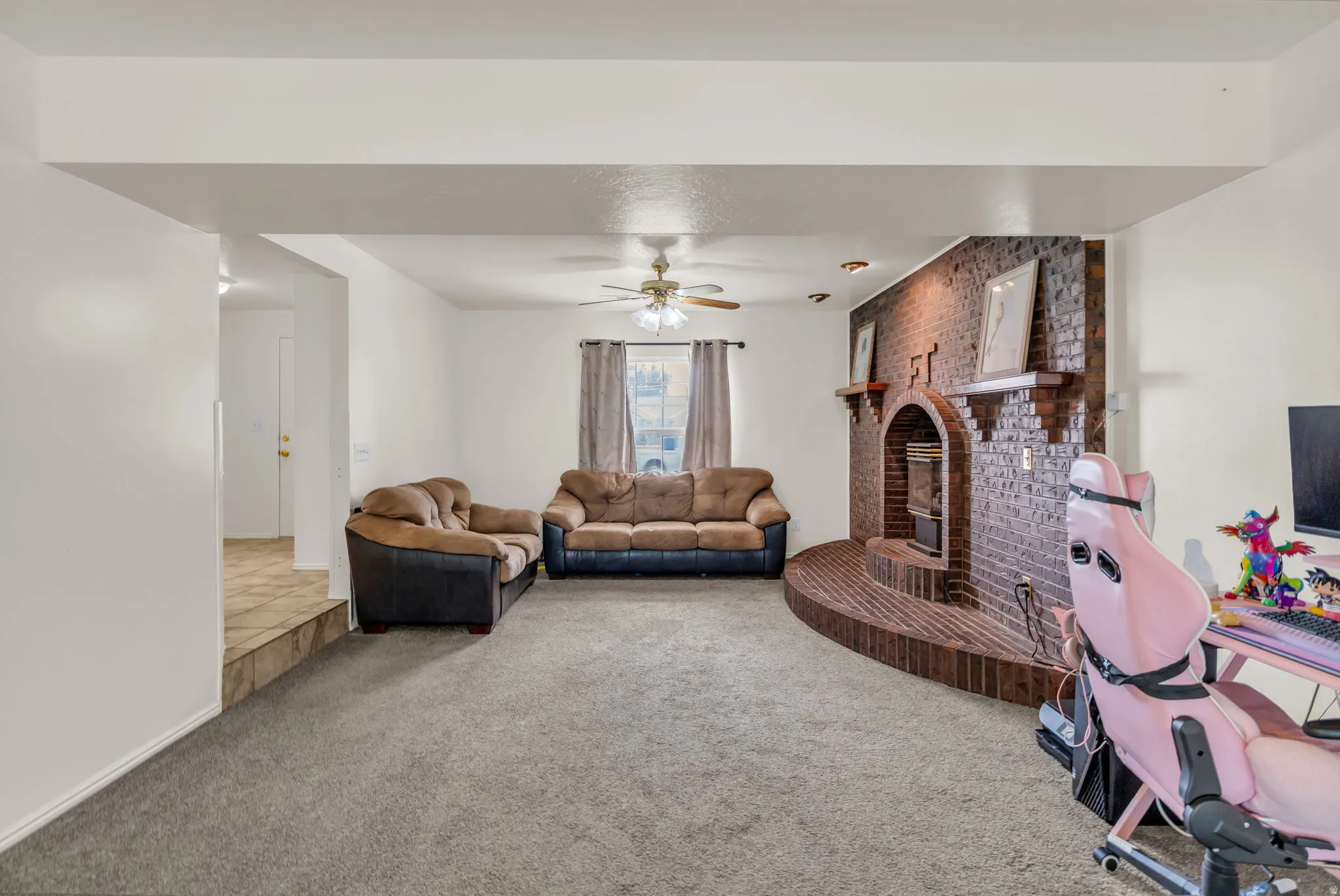 Living area featuring a brick-clad fireplace with hearth, recessed lighting, and a ceiling fan