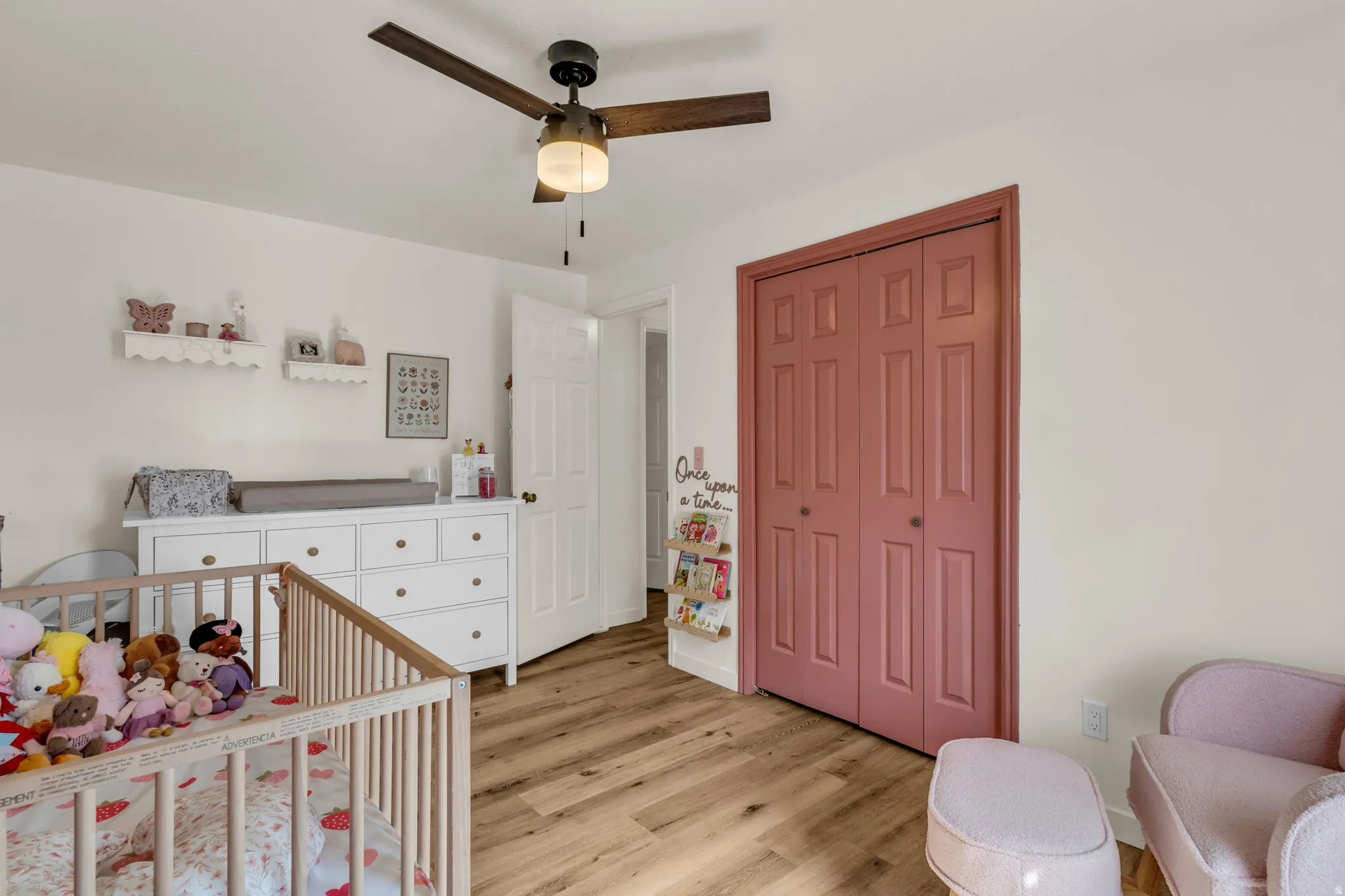 Wood-finish flooring, ceiling fan with integrated lighting, paneled closet doors, and recessed shelving