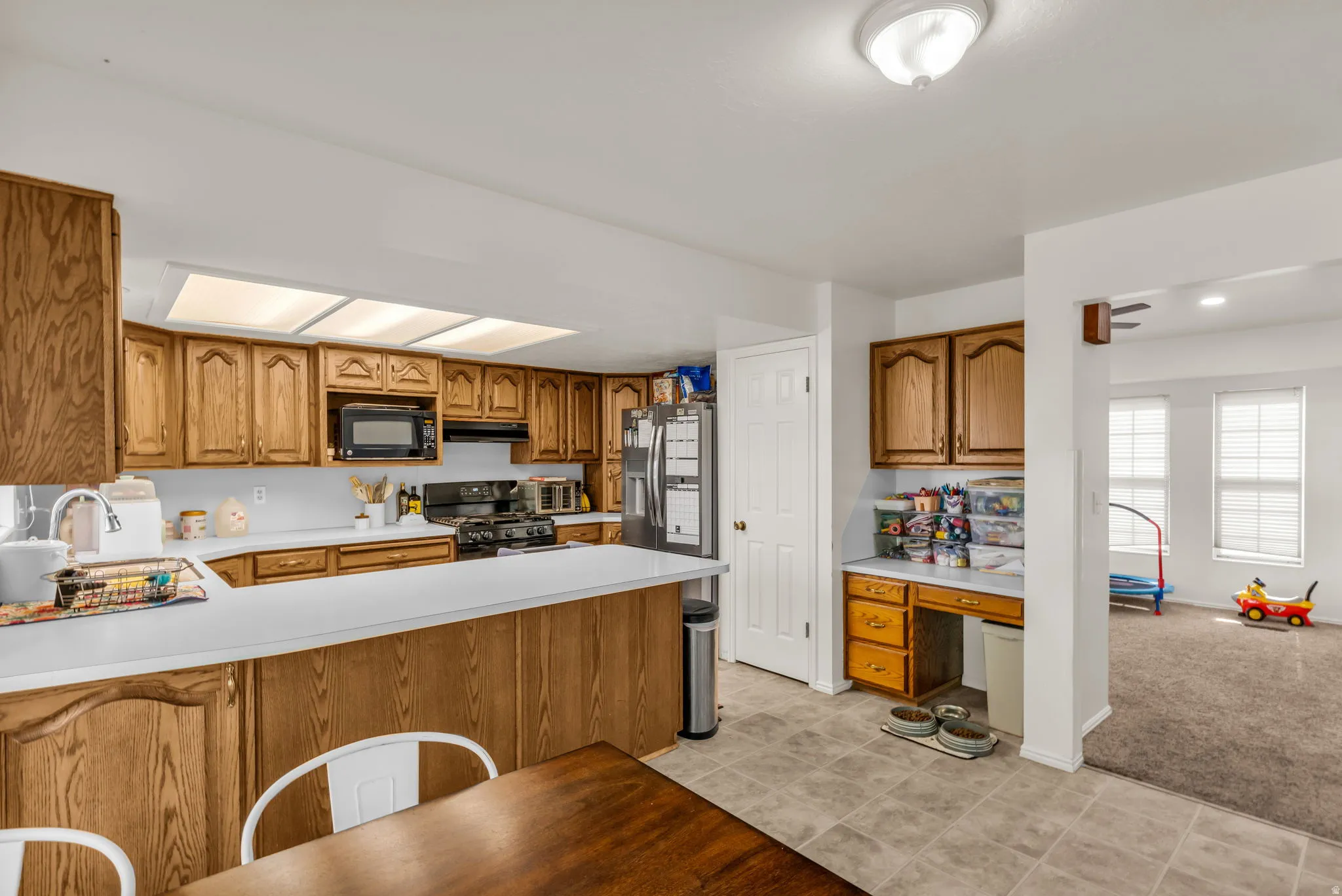 Kitchen featuring wood cabinetry, white countertops, tile flooring, and integrated desk area