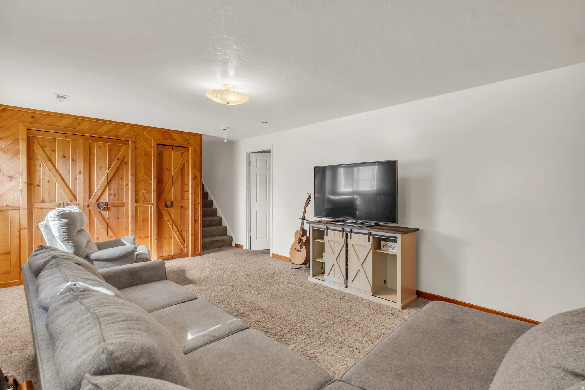 Carpeted living space featuring paneled wood-finish walls and built-in sliding barn doors