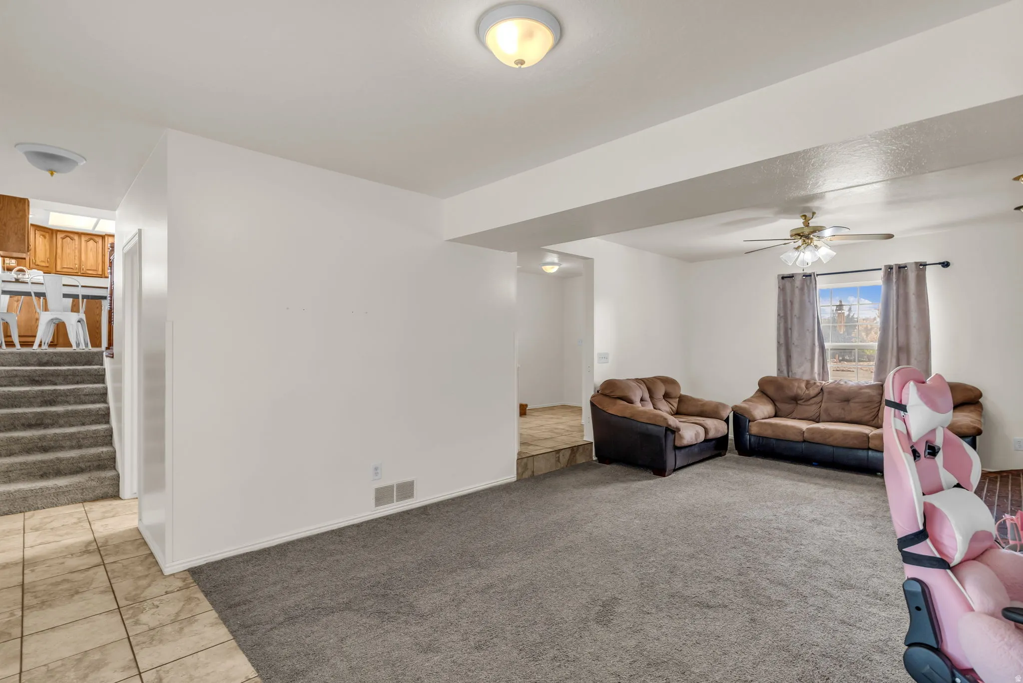Carpeted living area with overhead lighting and a ceiling fan