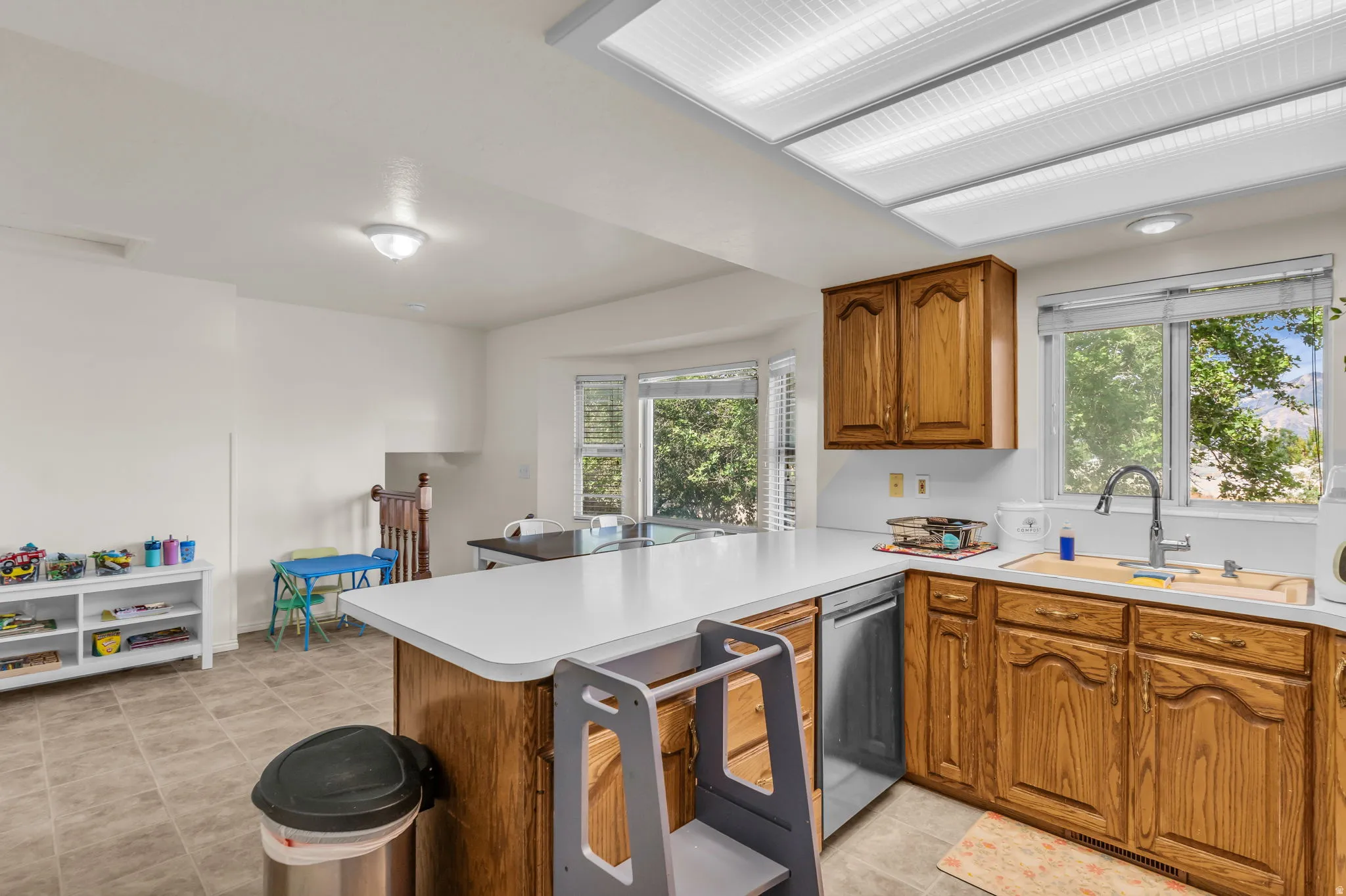 Open-concept kitchen with wood cabinetry, white countertops, and a stainless steel dishwasher
