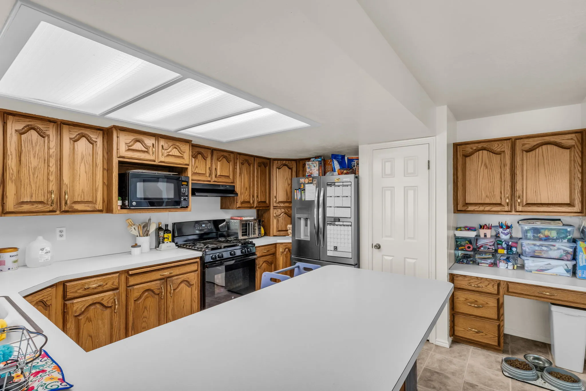 U-shaped kitchen featuring wood cabinetry, white countertops, built-in microwave, and a gas range