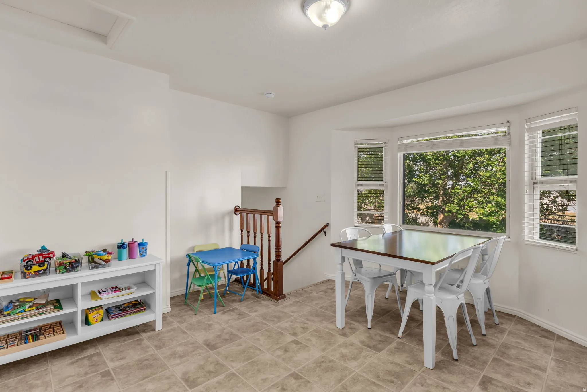 Bay window with multiple panes, ceramic tile flooring, and wood-toned stair railing