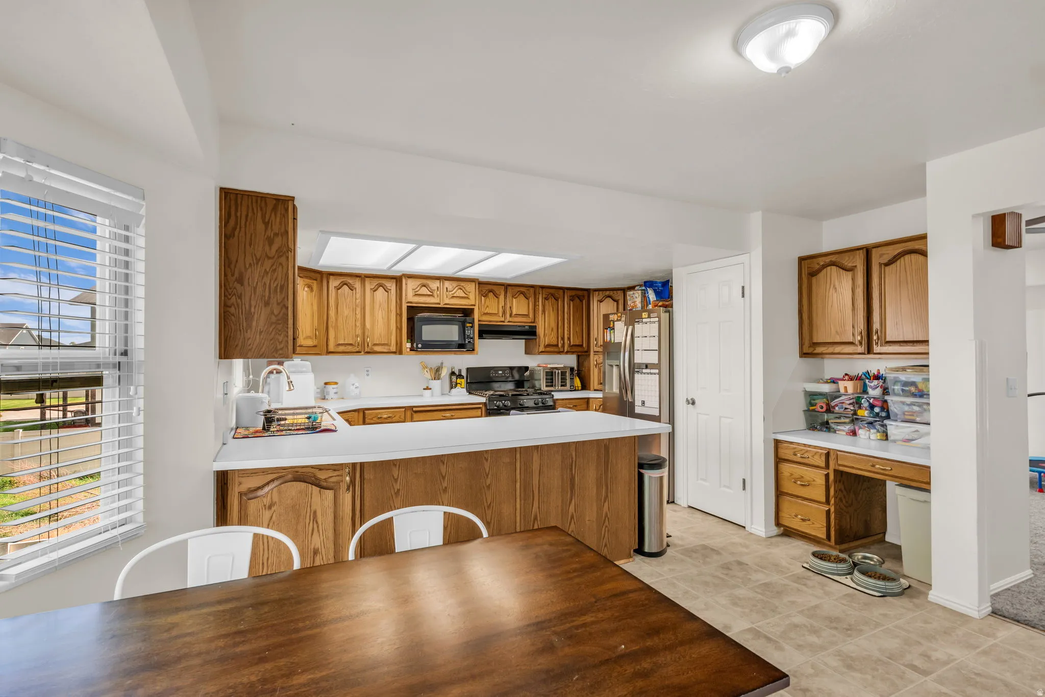Kitchen featuring wood-finish cabinetry, white countertops, a built-in oven, and a dining area with wood-finish flooring