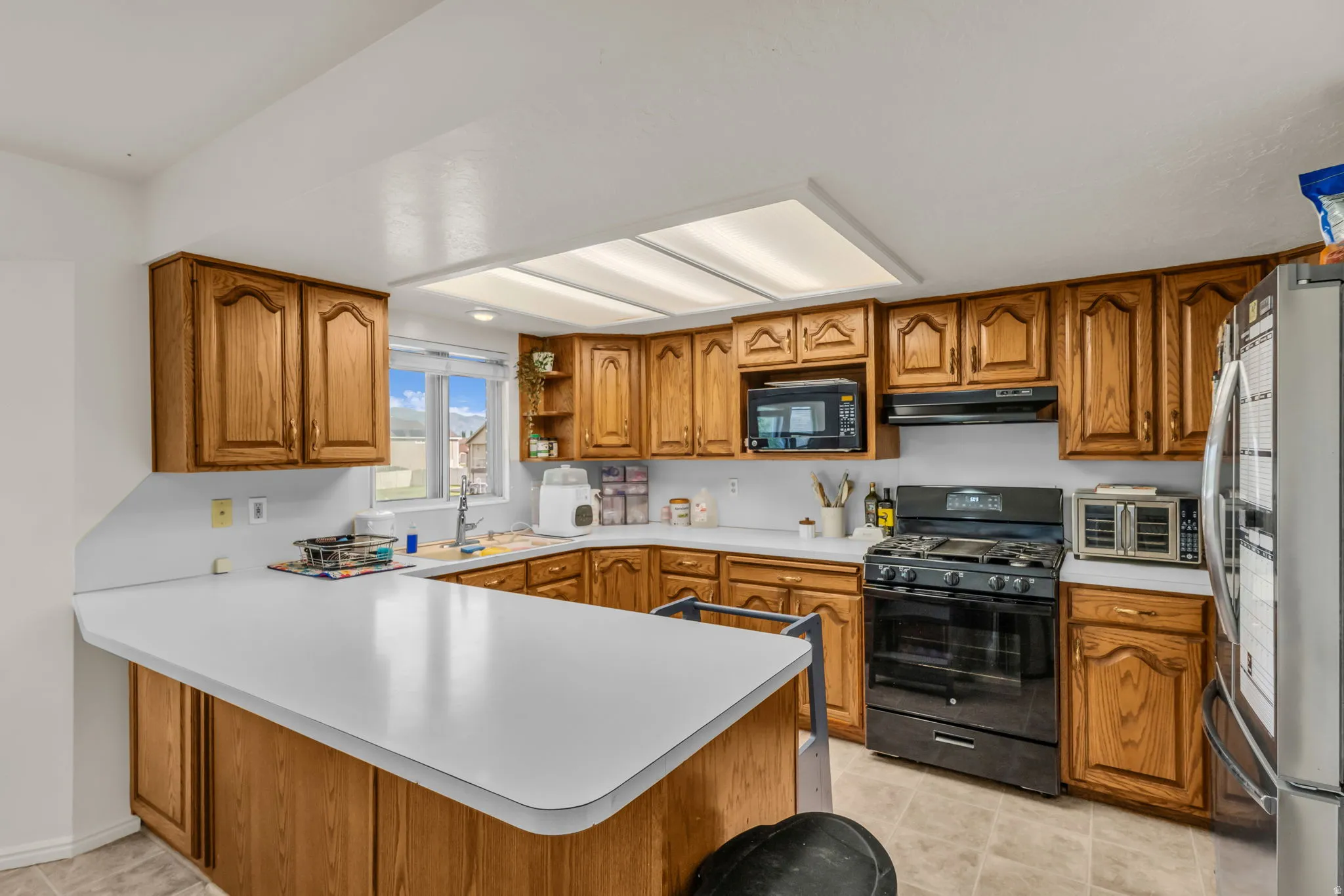 Kitchen featuring wood cabinetry, white countertops, a built-in microwave, and a gas range