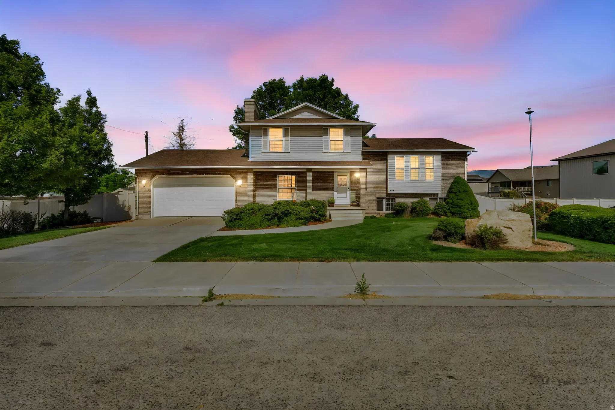 Two-story Colonial featuring a welcoming front elevation with dual-pane windows, a two-car garage with paneled door, and a professionally landscaped front yard with mature trees and manicured lawn