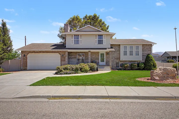 Two-story residence featuring a two-car garage, brick and siding exterior, front lawn, mature landscaping, and an inviting front walkway