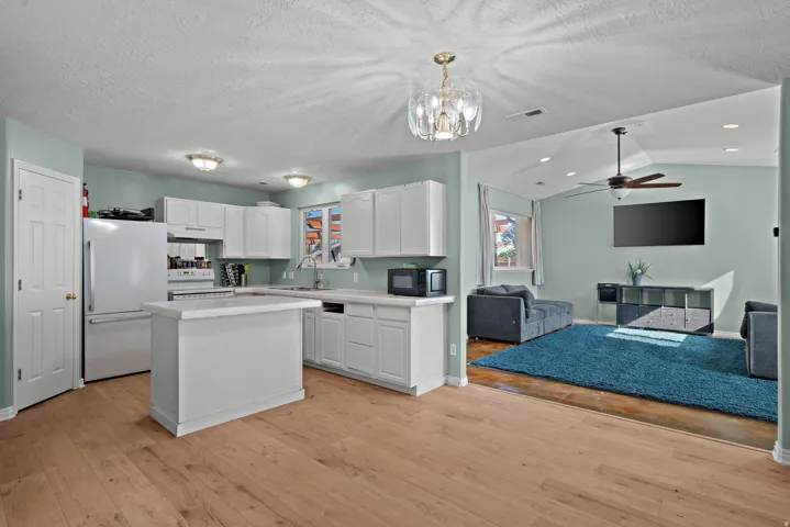 Kitchen with white cabinetry, a central island, and white appliances