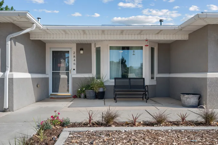 Covered front entry with a bay window, concrete walkway, and decorative landscaping