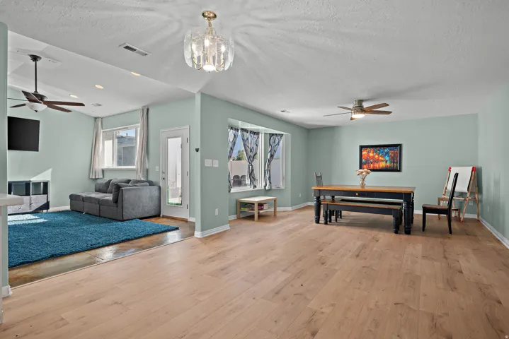 Wood-finish flooring throughout, with a decorative chandelier, recessed lighting, and ceiling fans