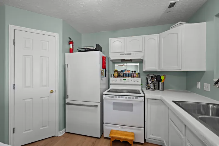 White cabinetry with brushed nickel hardware, light-toned countertops, and wood-finish flooring