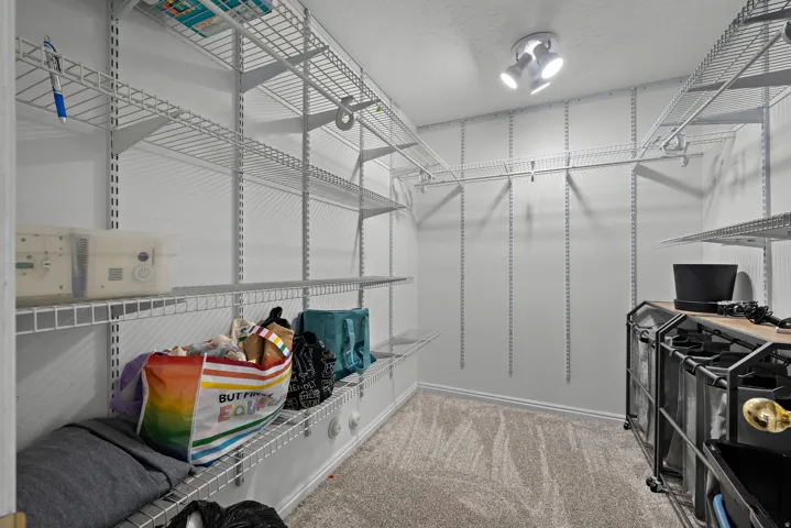 Walk-in closet with adjustable wire shelving, integrated hanging rods, and track lighting