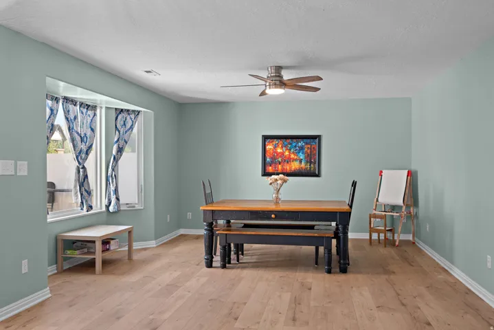 Recessed bay window, light wood-finish flooring, ceiling fan with integrated lighting, and neutral wall paint