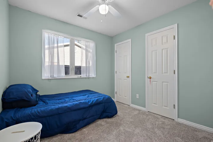 Bedroom featuring a ceiling fan, carpet flooring, and two white panel doors