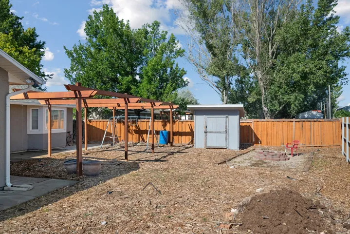 Wood pergola structure, built-in fire pit, privacy fencing, detached storage shed, and mature trees