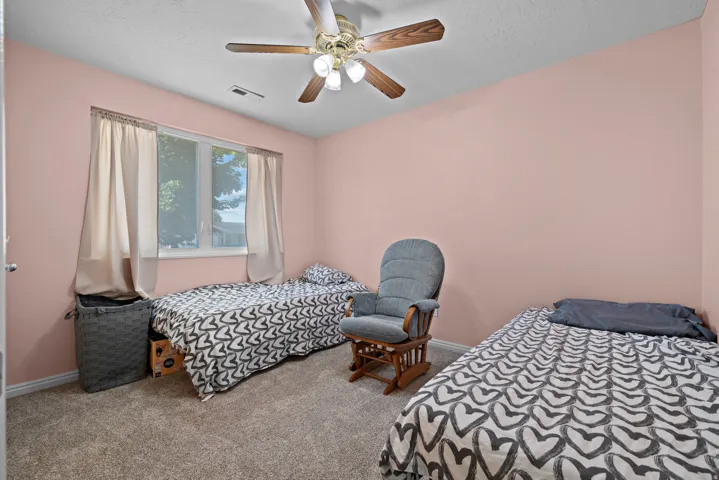 Ceiling fan with light fixture, window with exterior views, and carpet flooring