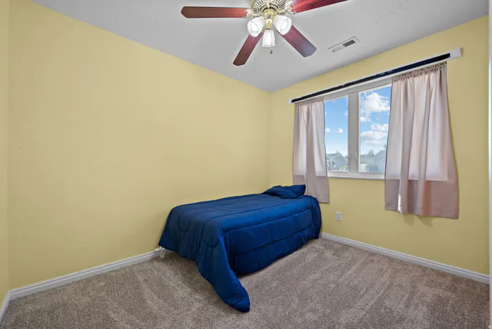 Room featuring a ceiling fan with integrated lighting, a double window, and carpeted flooring