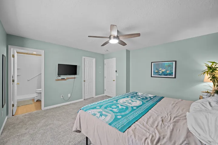 Recessed lighting, ceiling fan with integrated lighting, wall-mounted television, and a neutral color palette