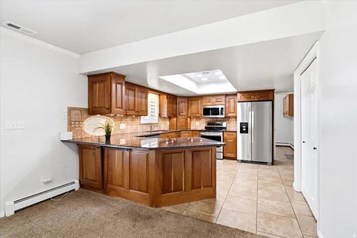 The open kitchen offers generous cabinetry, granite countertops, and a convenient breakfast bar overlooking the main living area.