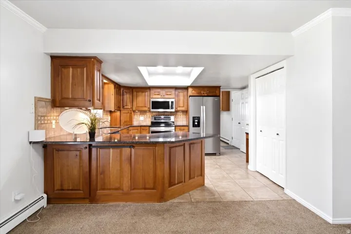 The open kitchen offers generous cabinetry, granite countertops, and a convenient breakfast bar overlooking the main living area.